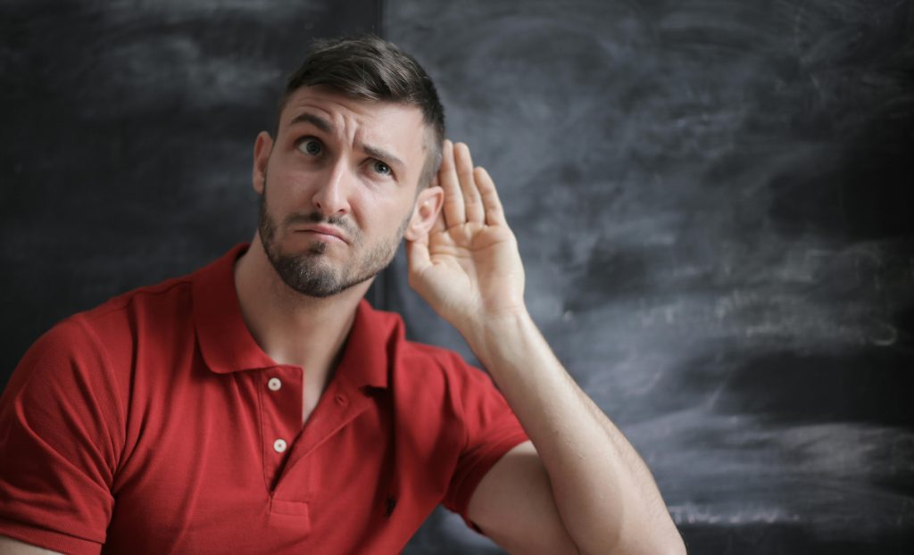 pexels-photo-3779448-3779448 Thoughtful man listening intently against a chalkboard background in a red polo shirt.